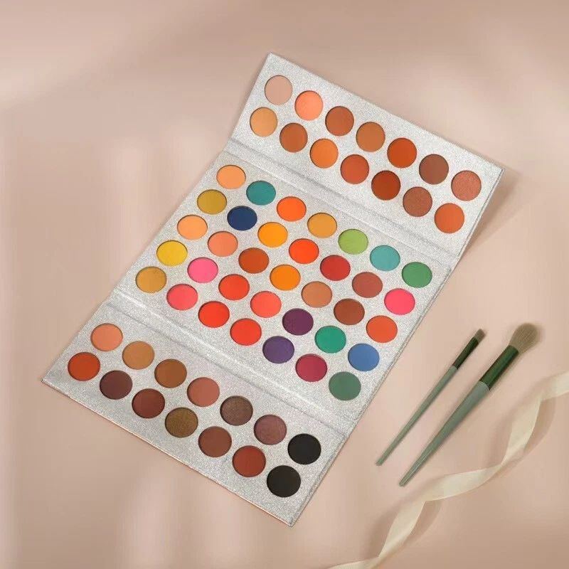 Makeup palette with colorful swatches and two brushes on a beige background