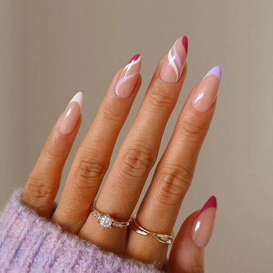 Hand with pink and white nail polish wearing gold rings on a neutral background