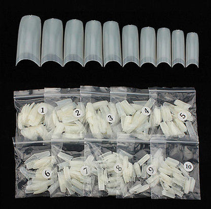 A set of 15 clear plastic nail tips arranged in a row above 10 numbered clear plastic bags containing white nail wraps, all photographed against a solid black background.