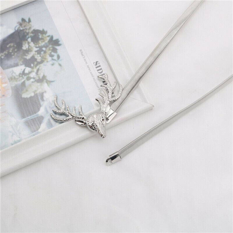 A silver-toned metal hair claw clip designed with a detailed deer head headpiece, displayed on a white textured surface next to a white picture frame.