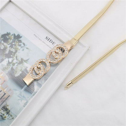 Gold-tone spiral hair claw clip embellished with clear rhinestones, shown with its matching elastic band on a white background next to a decorative card.