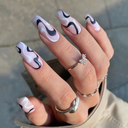 Hand with stylish black and white nail design wearing silver rings on a neutral background