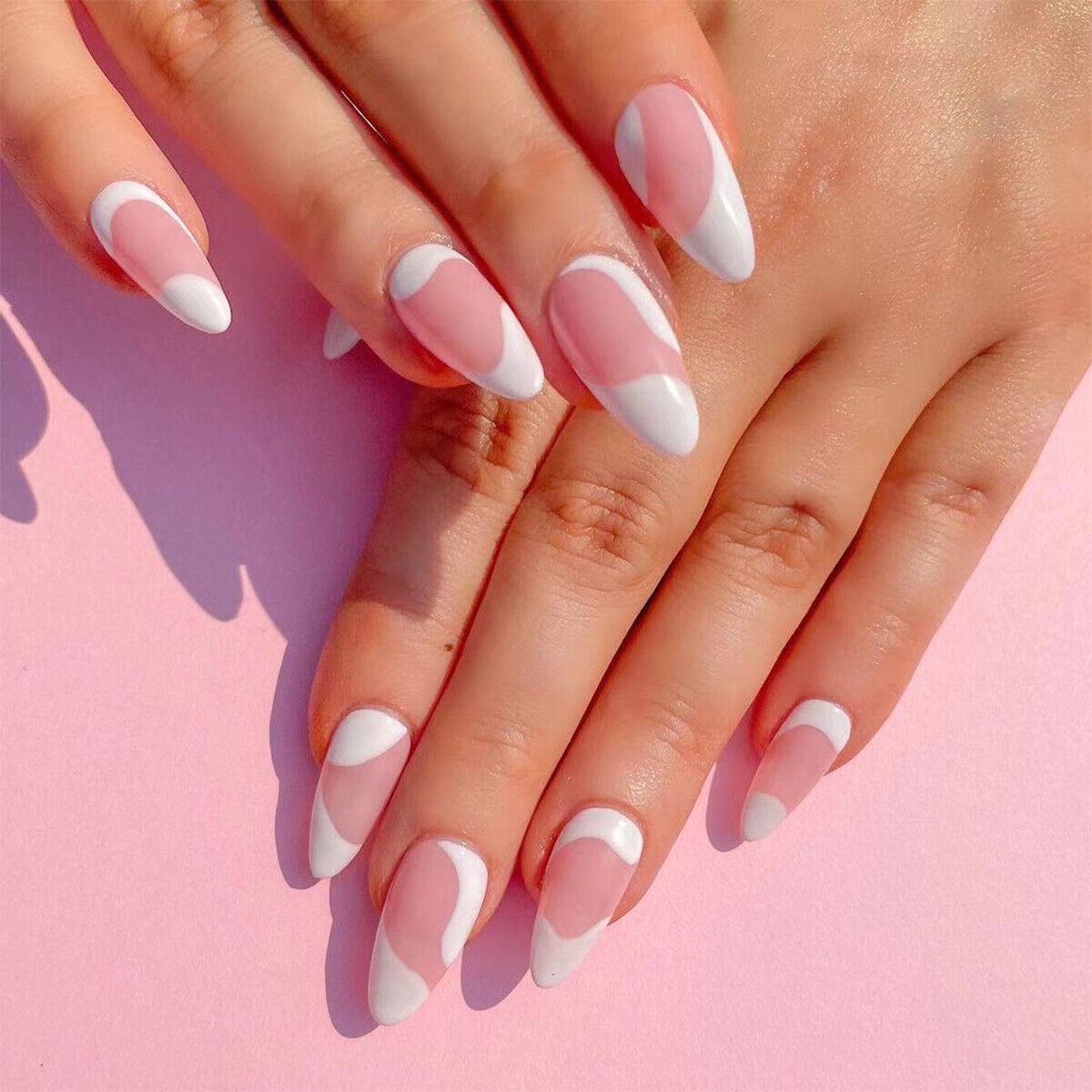 Close-up of hands with pink and white nail polish on a pink background