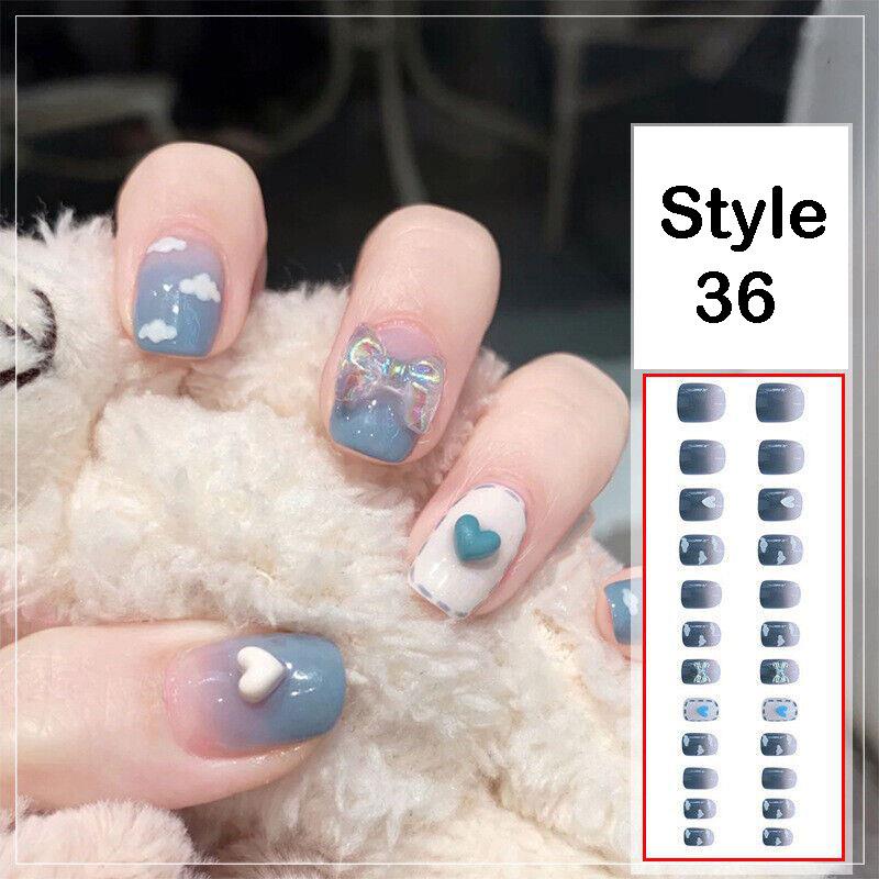 A hand with decorated fingernails in a blue and white style, resting on a white fluffy surface, next to a product sheet labeled 'Style 36' showing the nail wrap designs.