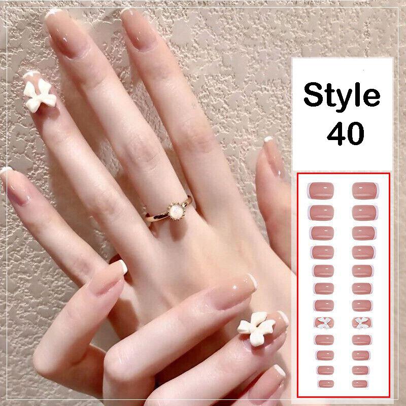 A hand with long, glossy, nude-pink press-on nails shown alongside a sheet labeled 'Style 40' containing matching nude rectangular nail tips and small white floral designs.