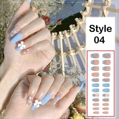 A close-up of a person's hands wearing press-on nails in a light blue and peachy-pink colorway with white floral accents, alongside a printed style sheet labeled 'Style 04' on a white background.