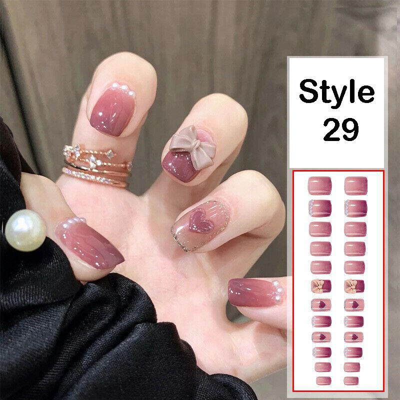 A hand wearing press-on nails in a dusty mauve-pink shade, with some nails decorated with small pearl clusters and a bow design. An inset on the right shows 'Style 29' with a grid of the nail designs.
