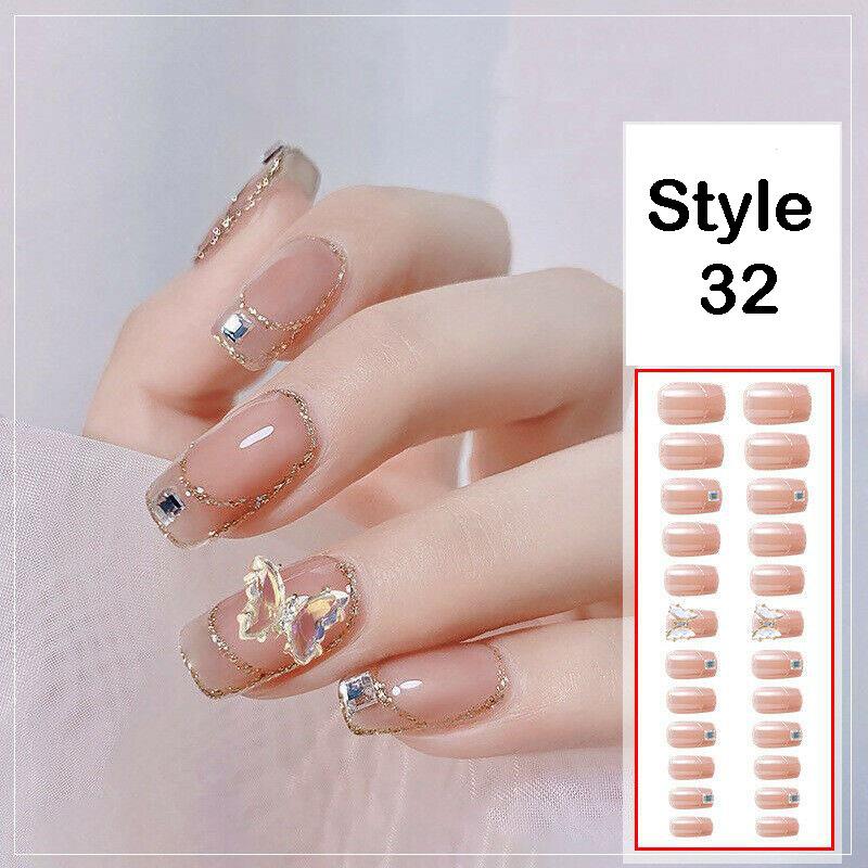 A hand displaying a set of natural nail wraps in a nude pink color with gold glitter borders and decorative rhinestone accents, alongside a white panel labeled 'Style 32' showing the total number of nail stickers included.