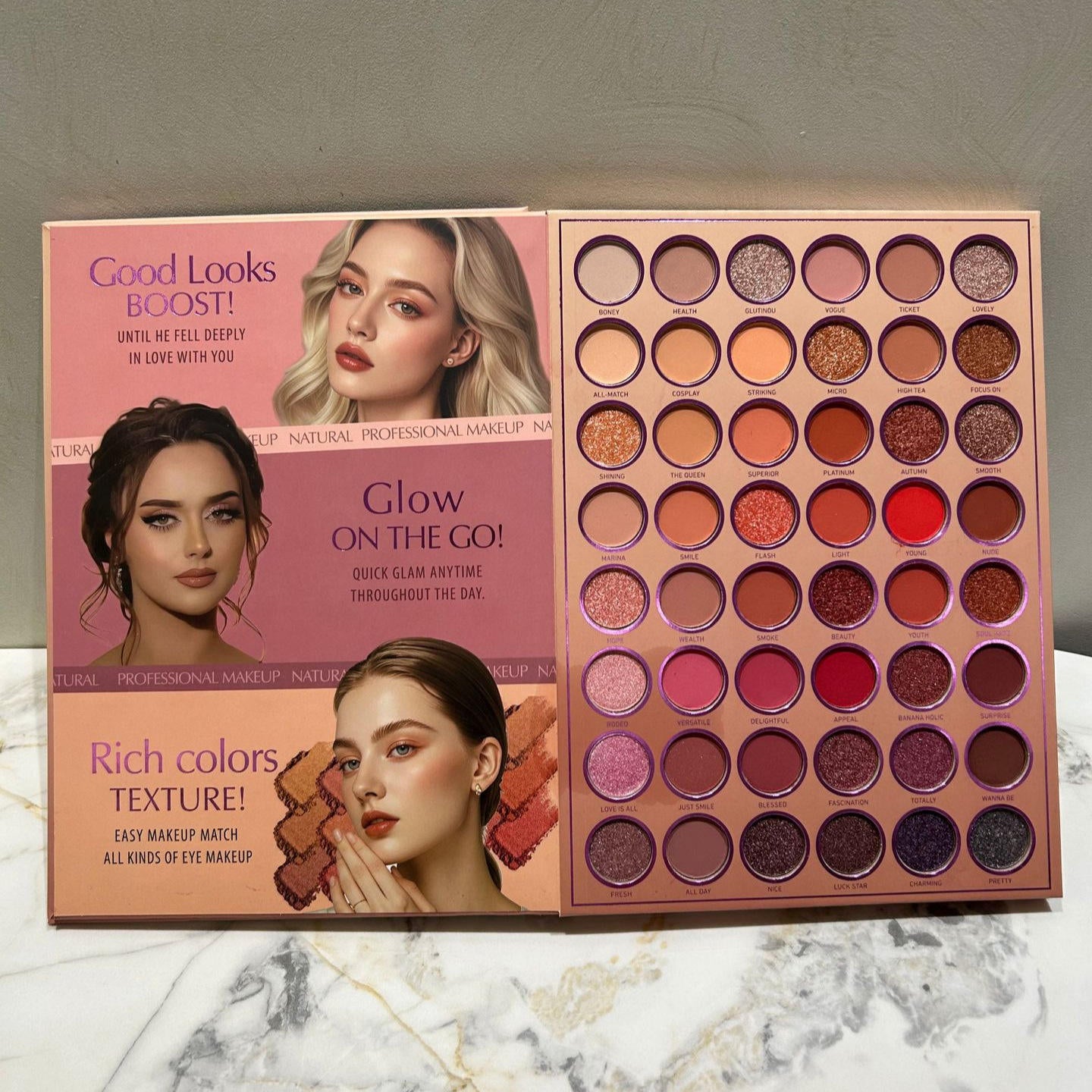 A professional makeup palette set displayed on a marble surface against a gray wall. The set includes three open palettes: 'Good Looks BOOST!', 'Glow on the GO!', and 'Rich colors TEXTURE!', showing a variety of eyeshadow shades ranging from neutrals and browns to pinks, purples, and reds.