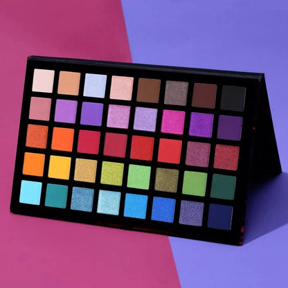Makeup palette with a variety of colorful shades on a pink and purple background