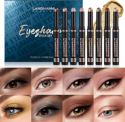 Langmanni Makeup Eyeshadow Stick Set featuring eight black cosmetic pencils with gold lettering, displayed alongside their blue patterned packaging box and a gold eyeshadow brush. Below, a grid of eight close-up eye swatches demonstrates the various eyeshadow colors and finishes.