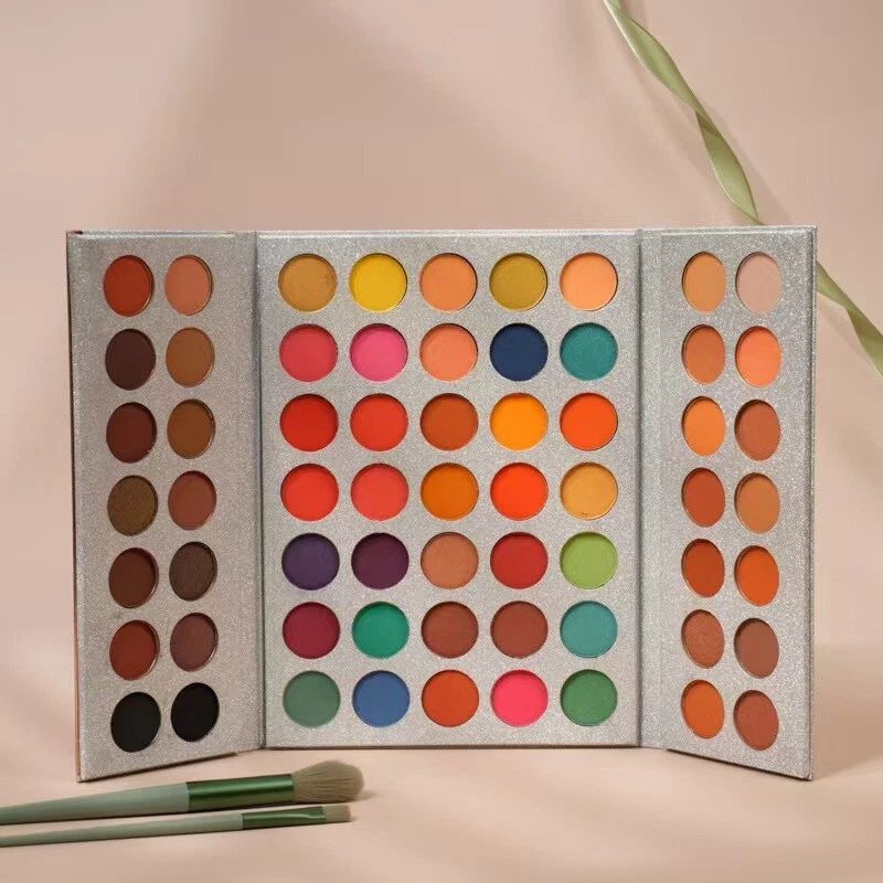 Makeup palette with colorful eyeshadows and two brushes on a beige background