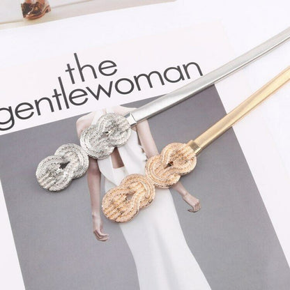 A pair of gold and silver split-tone hair pins with textured, woven circular details, displayed on a fashion magazine page.