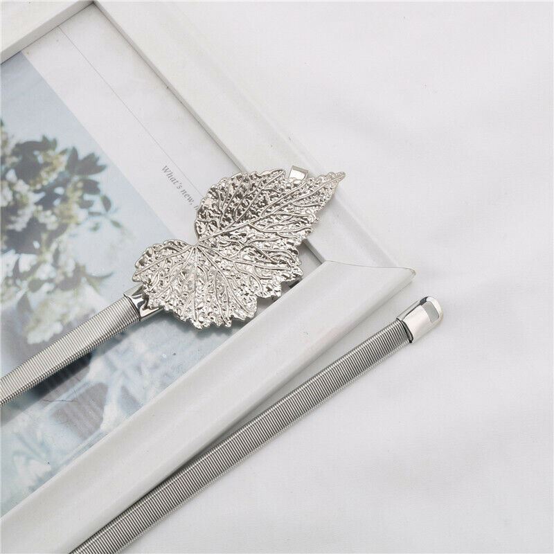 A silver metal mesh pen with a decorative leaf-shaped clip, resting on a white picture frame against a white fabric background.