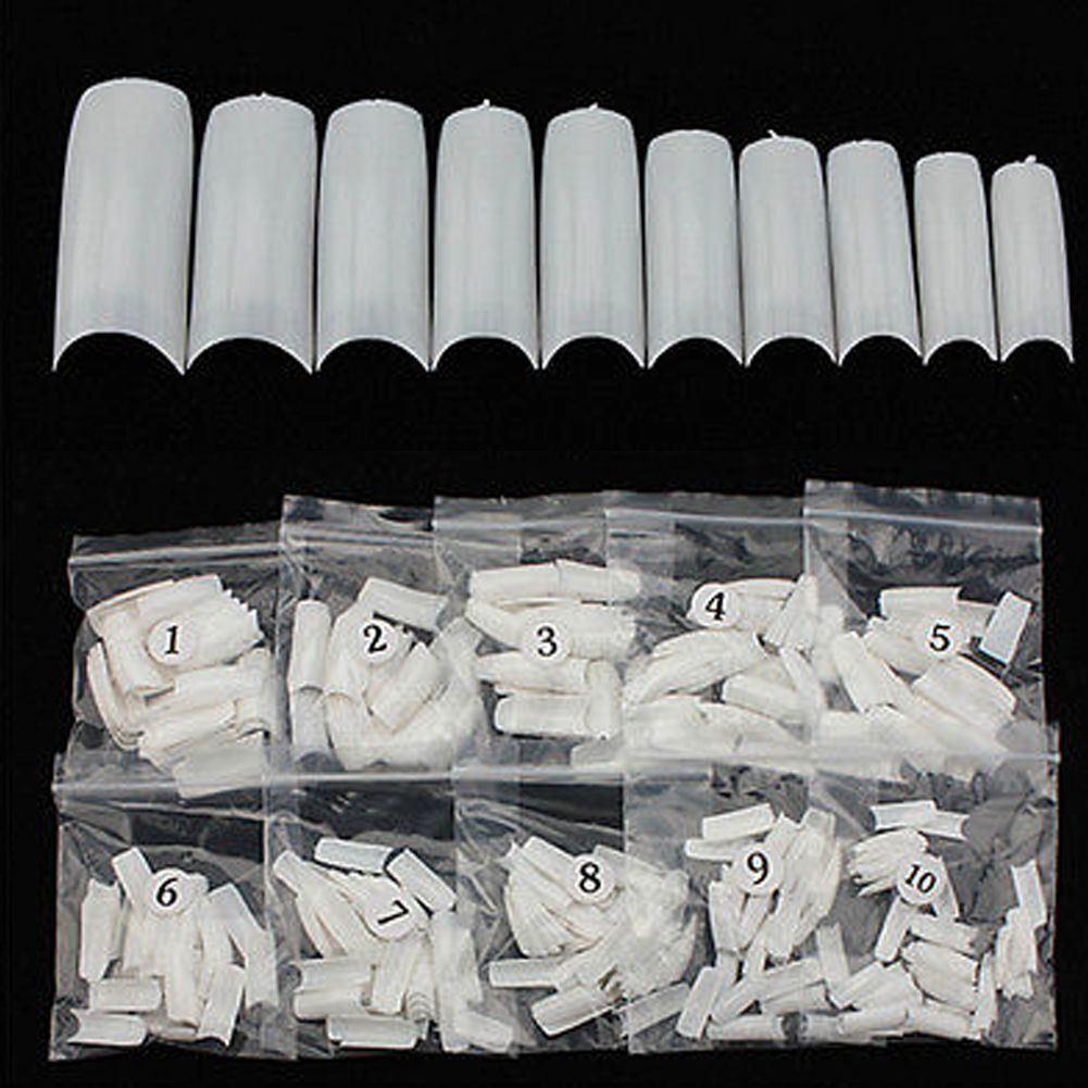 White artificial nail tips arranged in a row above clear plastic bags labeled 1 through 10, showing different lengths and shapes of nail extensions on a black background.