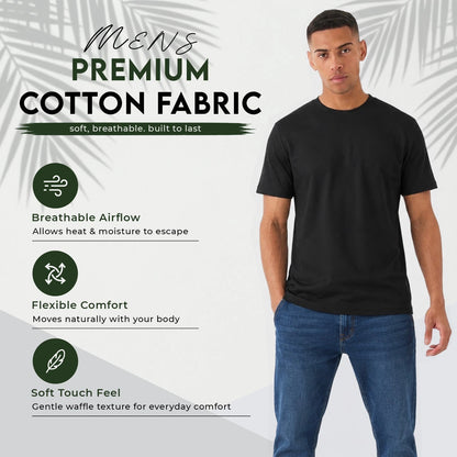 A man wearing a black short-sleeve cotton t-shirt and blue jeans stands against a light gray background with palm leaf graphics and text highlighting fabric features: breathable airflow, flexible comfort, and soft touch feel.