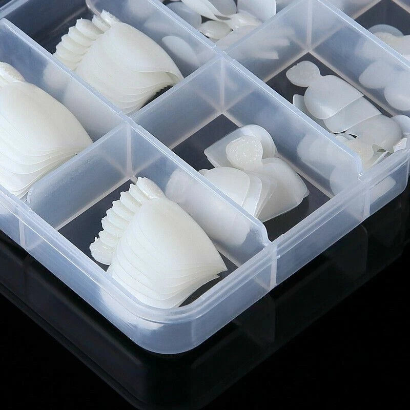 A clear plastic organizer tray with multiple compartments holding small white silicone or rubber pieces, photographed on a black reflective surface.