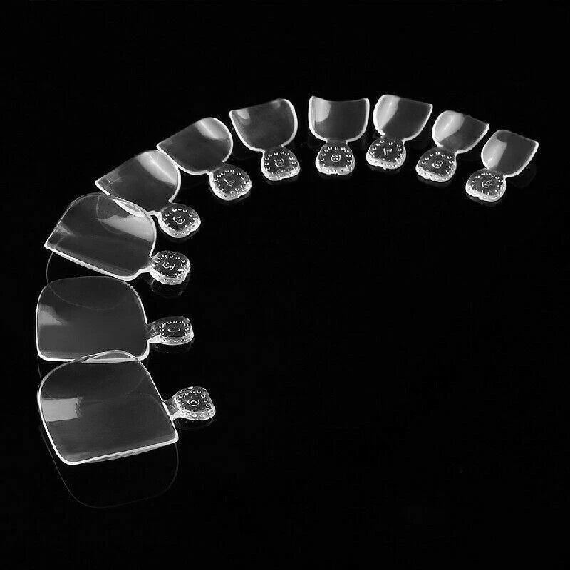 A set of clear, transparent nail tips arranged in a curved row on a solid black background.